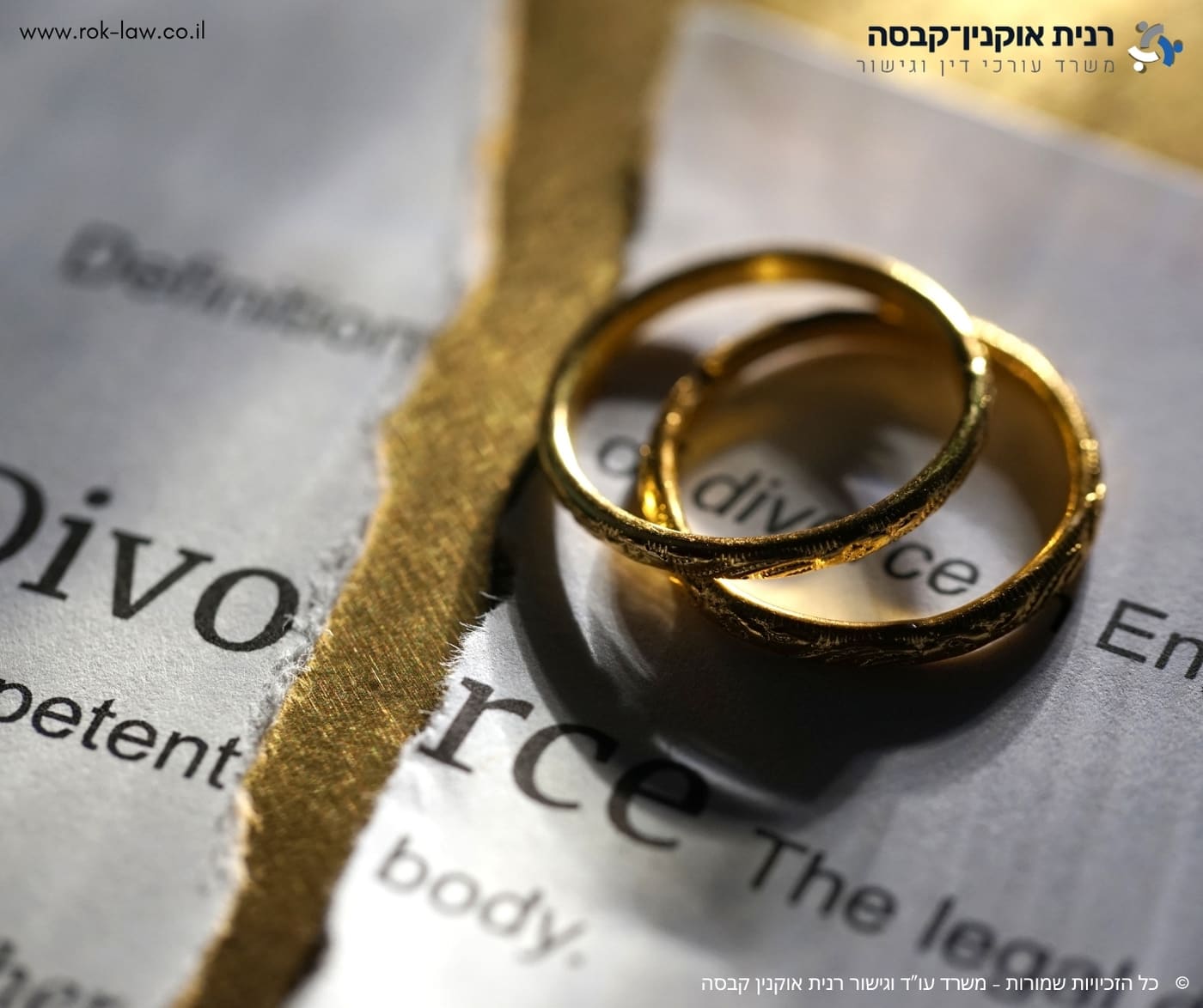 שתי טבעות נישואין מונחות על דף מילון שבו המילה Divorce, קרוע לשניים